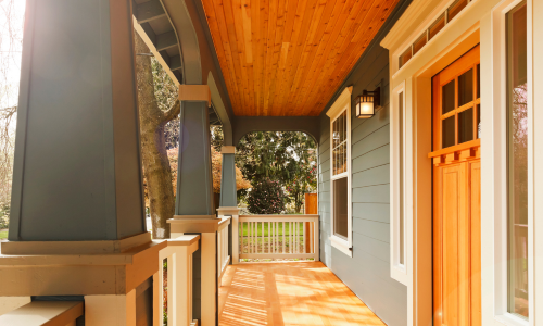 A porch with a wooden ceiling and white railing