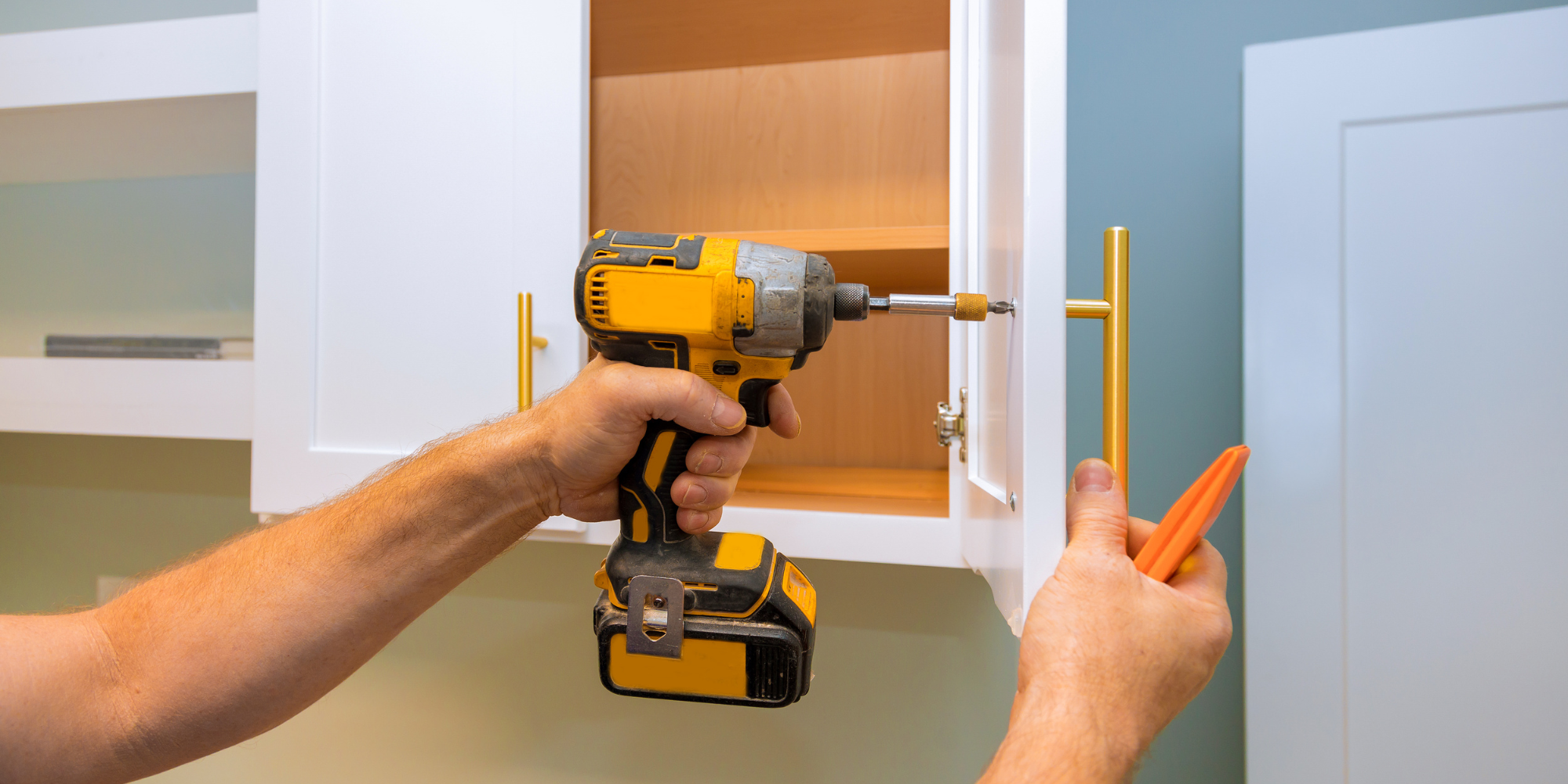 A man is holding a drill and a screwdriver