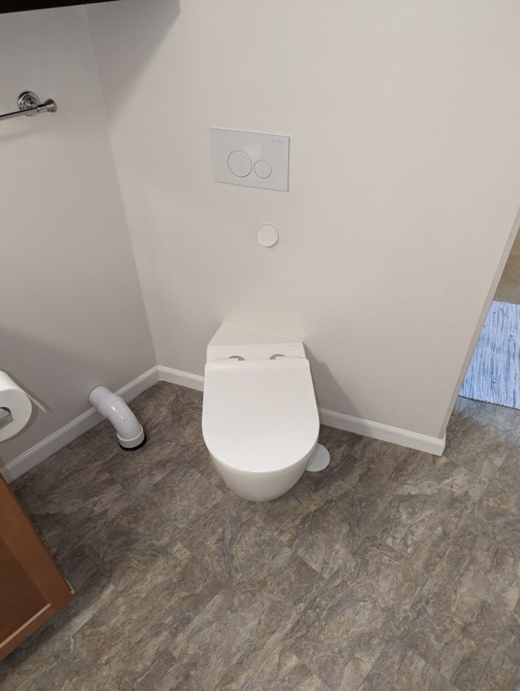 A white toilet sitting in a bathroom next to a toilet paper dispenser